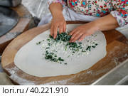 Turkish woman prepares Gozleme - traditional dish in the form of flatbread stuffed with greens and cheese, wrapped inside. Baked in a pan called a saj. Selective focus (2019 год). Стоковое фото, фотограф Виктория Панченко / Фотобанк Лори
