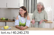 Senior woman scolding her adult daughter cooking breakfast in kitchen. Стоковое видео, видеограф Яков Филимонов / Фотобанк Лори