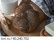 Классическая пшеничная коса или плетёнка с маком. Вкусный хлеб крупным планом. Свежеиспеченный хлеб на закваске с золотистой корочкой на деревянной доске. Контекст пекарни с вкусным хлебом. Кондитерские изделия. Стоковое фото, фотограф Photojuli / Фотобанк Лори