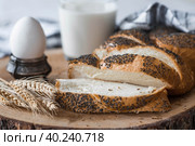 Классическая пшеничная коса или плетёнка с маком. Вкусный хлеб крупным планом. Свежеиспеченный хлеб на закваске с золотистой корочкой на деревянной доске. Контекст пекарни с вкусным хлебом. Кондитерские изделия. Стоковое фото, фотограф Photojuli / Фотобанк Лори