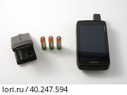 Russia, Naberezhnye Chelny, February 11, 2023: garmin travel navigator with batteries and AA battery pack on white background. Copy space. Редакционное фото, фотограф Роман Дзюбало / Фотобанк Лори