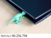 Крышка ноутбука прищемила голову маленькому зеленому динозавру. Стоковое фото, фотограф Vladimir Vikhrov / Фотобанк Лори