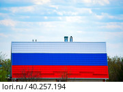 The roof of a residential building in the form of a Russian flag against the background of a cloudy daytime sky. Russian tricolor. Стоковое фото, фотограф Антон Вахрушев / Фотобанк Лори