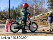 Маленький велосипедист стоит на памп-треке весной во Всеволожске (2023 год). Редакционное фото, фотограф Евгения Колодкина / Фотобанк Лори