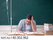Young male teacher suffering in the classroom. Стоковое фото, фотограф Elnur / Фотобанк Лори