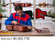 Young man repairing musical instruments at workshop. Стоковое фото, фотограф Elnur / Фотобанк Лори