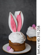 Beautiful stylish still life. Easter cake with rabbit ears, meringue, marshmallows, Easter eggs and willow twigs on a dark background. happy Easter. Стоковое фото, фотограф Photojuli / Фотобанк Лори