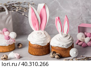 Beautiful stylish still life. Easter cake with rabbit (hare) ears, meringue, marshmallows, Easter eggs and willow branches and on a light concrete background. Happy Easter. Стоковое фото, фотограф Photojuli / Фотобанк Лори
