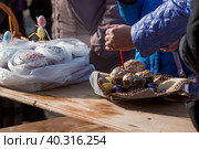Russia, the City of Vidnoye, April 15, 2023. Easter service. The priest sprinkles people and Easter treats with holy water at the entrance to the temple. People go to sanctify eggs and cakes. Стоковое фото, фотограф Photojuli / Фотобанк Лори