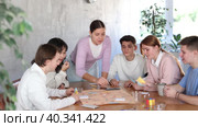 Cheerful adult students playing board game excitedly sitting around the table. Стоковое видео, видеограф Яков Филимонов / Фотобанк Лори