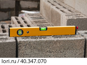 The bubble construction level lies on a cinder block construction stone. It is used to assess the compliance of surfaces with a vertical or horizontal plane, as well as to measure the angular deviate. Стоковое фото, фотограф Неведицына Елена / Фотобанк Лори