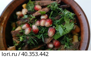 Мясо с ароматными травами и зернами граната. Вкусное мясное блюдо в глиняном горшочке. Ресторан грузинской кухни. Вкусная и здоровая еда. Запеченная баранина или говядина крупным планом. Замедленная съемка. Meat with aromatic herbs and pomegranate seeds. Delicious meat dish in a clay pot. Georgian cuisine restaurant. Delicious and healthy food. Baked lamb or beef close-up. Slow motion. Стоковое видео, видеограф Ирина / Фотобанк Лори