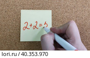 2+2=5. Арифметическое уравнение с ошибкой. Простое математическое уравнение на желтой наклейке. Женская рука пишет красным маркером. Концепция командной работы, синергии. Рукописные цифры и знаки. An arithmetic equation with an error. A simple mathematical equation on a yellow sticker. A woman's hand writes with a red marker. The concept of teamwork, synergy. Handwritten numbers and signs. Стоковое видео, видеограф Ирина / Фотобанк Лори