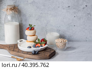 Cottage cheese pancakes, Russian cheesecakes with fresh blueberries, strawberries and mint on a stylish wooden board on a gray concrete table. Natural products. Healthy and delicious breakfast. Стоковое фото, фотограф Photojuli / Фотобанк Лори