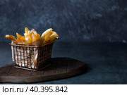 French fries in a metal basket with salt on a stylish board on a dark background. Fried potatoes. The concept of fast food and junk food. Стоковое фото, фотограф Photojuli / Фотобанк Лори
