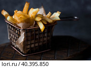 French fries in a metal basket with salt on a stylish board on a dark background. Fried potatoes. The concept of fast food and junk food. Стоковое фото, фотограф Photojuli / Фотобанк Лори