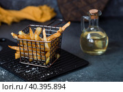 French fries in a metal basket with salt, ketchup and sunflower oil on a stylish board on a dark background. Fried potatoes. The concept of fast food and junk food. Стоковое фото, фотограф Photojuli / Фотобанк Лори