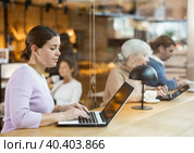 Young millennial woman sitting at table, using laptop and enjoing cup of tea in coffee house. Modern female lifestyle concept. Стоковое фото, фотограф Яков Филимонов / Фотобанк Лори