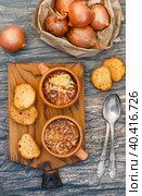 Two servings of traditional French onion soup with baguette and gruyere cheese (emmental, comte or beaufort) in ceramic bowls on a wooden background. Selective focus. Стоковое фото, фотограф Виктория Панченко / Фотобанк Лори