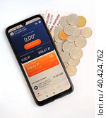 НПД (самозанятость). В личном кабинете телефона с открытым приложением «Мой налог» указана сумма налогов за  предыдущий месяц. Телефон лежит на фоне приготовленных для оплаты денег (2023 год). Редакционное фото, фотограф Олег Безруков / Фотобанк Лори