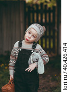 A little boy of 4 years old outdoors with a suitcase and a stuffed rabbit goes on a journey. A beautiful portrait of a child playing on the street. Стоковое фото, фотограф Photojuli / Фотобанк Лори