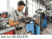 Close up of automechanic using cellphone at workplace in car service. Стоковое фото, фотограф Сергей Толмачёв / Фотобанк Лори