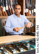 Hispanic seller of gun shop showing hunting skinner knife. Стоковое фото, фотограф Яков Филимонов / Фотобанк Лори