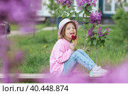 Lifestyle. A beautiful little girl in pink clothes with a lollipop in the shape of a heart. The girl licks the candy. The concept of love and sweets. Стоковое фото, фотограф Photojuli / Фотобанк Лори