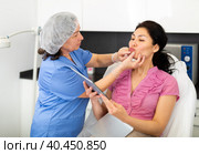 Cosmetologist planning upcoming lip reshaping procedures for female patient. Стоковое фото, фотограф Яков Филимонов / Фотобанк Лори
