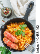 Stewed cabbage with carrots, onions and tomatoes and sausages in bacon with parsley and spices in a cast iron pan. Bigos. Delicious lunch. Стоковое фото, фотограф Виктория Панченко / Фотобанк Лори