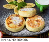Syrniki or cheese pancakes with cream sauce and bananas on a plate on wooden table close up. Стоковое фото, фотограф Татьяна Терехина / Фотобанк Лори