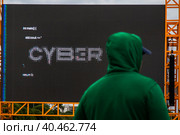 Молодой человек смотрит на экран киберфестиваля Positive Hack Days в Парке Горького города Москвы, Россия (2023 год). Редакционное фото, фотограф Николай Винокуров / Фотобанк Лори