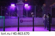 People skate in the evening on a lighted ice rink. A blizzard is raging and snow is falling. Zelenograd, Russia 28.01.2022. Редакционное видео, видеограф Юрий Поздников / Фотобанк Лори