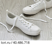 White sneakers with untied laces are on floor. Стоковое фото, фотограф Володина Ольга / Фотобанк Лори