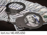 One hundred dollar bills and steel handcuffs close up. Стоковое фото, фотограф Артем Курутин / Фотобанк Лори