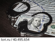 One hundred dollar bills and steel handcuffs close up. Стоковое фото, фотограф Артем Курутин / Фотобанк Лори