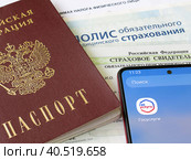 Персональные данные гражданина РФ: паспорт, медицинский полис, СНИЛС и телефон с электронным приложением Государственные слуги (2023 год). Редакционное фото, фотограф Татьяна Т / Фотобанк Лори