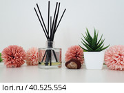 Composition of pink artificial flowers, incense sticks in a glass vase with essential oil. Still life on a white table. Aloe flower in a white pot. Room and apartment decor, interior design. Стоковое фото, фотограф Юлия Петровская / Фотобанк Лори