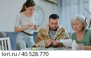 Portrait of focused elderly woman sitting at table reading instruction choosing medicines for her sick adult son, while her daughter-in-law trying to help and giving drugs to him. Стоковое видео, видеограф Яков Филимонов / Фотобанк Лори