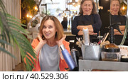 Delighted young female client sitting in hairdressing chair after haircut from professional stylist. Стоковое видео, видеограф Яков Филимонов / Фотобанк Лори
