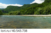 Замедленная съемка красивой горной реки с прозрачной водой на фоне зеленых горных склонов, голубого неба и облаков. Красота нетронутой природы. Стоковое видео, видеограф Воловодов Владимир / Фотобанк Лори