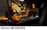 Jack-o'-lantern and Halloween decorations at the workplace of a professional gamer and esports player. Dark interior with festive illumination. 3D render. Стоковое фото, фотограф Енваев Андрей / Фотобанк Лори