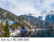 A man in takes a picture of a beautiful winter landscape of the Caucasus mountains and Lake Ritsa. Стоковое фото, фотограф Ирина Кононова / Фотобанк Лори
