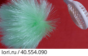 A man demonstrating the power of the airflow of a portable fan. Blows them a brush from different sides. On a coral background. Close-up. Стоковое видео, видеограф Vadzim Yakubovich / Фотобанк Лори
