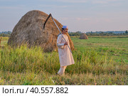 An senior asian. man in a skullcap and traditional clothes leaves with a hand scythe from the hay field at sunset. Стоковое фото, фотограф Ирина Кононова / Фотобанк Лори