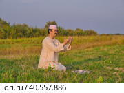 A Muslim senior man wearing an embroidered skullcap and white traditional clothes prays. Стоковое фото, фотограф Ирина Кононова / Фотобанк Лори