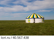 Россия, Калмыкия. 04.20.2019: Белая юрта, украшенная рисунками лотосов, стоит в степи под голубым небом. Редакционное фото, фотограф Ольга Шуклина / Фотобанк Лори