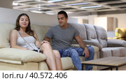Newlyweds choose upholstered furniture in store and carefully feel cotton covering of seat. Стоковое видео, видеограф Яков Филимонов / Фотобанк Лори