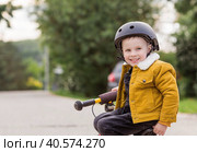 A cheerful little boy rides a running bike in a helmet outdoors. A happy child is engaged in an active sport. Protection. Life insurance and child safety. Стоковое фото, фотограф Photojuli / Фотобанк Лори