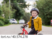 A cheerful little boy rides a running bike in a helmet outdoors. A happy child is engaged in an active sport. Protection. Life insurance and child safety. Стоковое фото, фотограф Photojuli / Фотобанк Лори